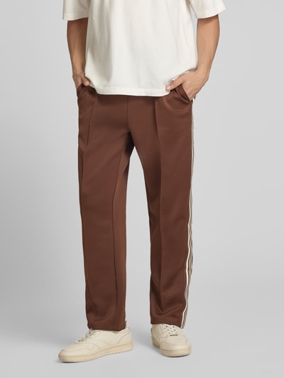 Mannenmodel draagt Regular Fit Sweatpants mit elastischem Bund Modell 'RIBER' van Only & Sons in effen bruin met contrasterende strepen, fijne weefstructuur, zijzakken, elastische taille met koord. Volledige lichaamsvooraanzicht.