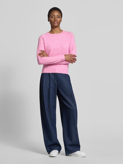 Kobiece model nosi Regular Fit Pullover mit Streifen model 'DOFFY' od VERO MODA, różowy sweter, ciemnoniebieskie spodnie, białe buty, Ganzkörperansicht von vorne.