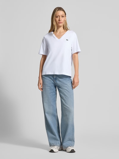 Frauenmodel trägt Relaxed Fit T-Shirt aus reiner Baumwolle von Lacoste, Optik: Unifarben, Logo-Stitching, V-Ausschnitt, Ganzkörperansicht von vorne.