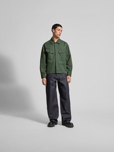 Männermodel trägt Regular Fit Hemdjacke aus Baumwolle von Kenzo in Dunkelgrün mit Brusttaschen, Umlegekragen, verdeckter Knopfleiste, Ganzkörperansicht von vorne.