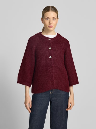 Vrouwenmodel draagt Relaxed Fit Cardigan met wol-aandeel Model 'Lulu' van FREE/QUENT, elastische wolmix, tricotlook, 3/4-mouw, ruglengte maat S 59 cm, mouwlengte maat S 48 cm, donkerrode kleur, rechte vormen, zachte textuur, volledige lichaamsaanzicht van voren.