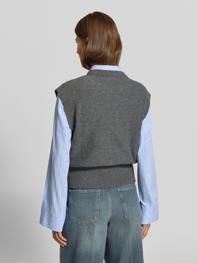 Frauenmodel trägt Regular Fit Pullunder mit Woll-Anteil von MYON in Grau, Strick-Optik, kombiniert mit Jeans, Ganzkörperansicht Rückansicht.