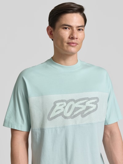 Männermodel trägt Regular Fit T-Shirt aus reiner Baumwolle Modell 'TE_BAYMESH' von BOSS Orange in Hellblau mit Mesh-Details, Nahaufnahme Oberkörper.