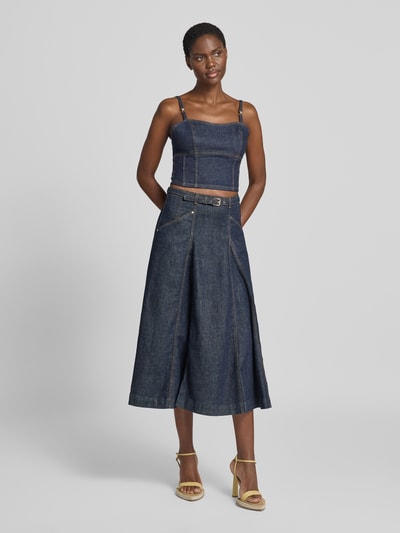 Frauenmodel trägt Jeansrock mit Gürtel Modell 'RAYNE' von GUESS, A-Linie, Midirock in Dunkelblau, Baumwoll-Mix, Ganzkörperansicht von vorne.