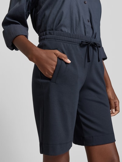 Frauenmodel trägt Shorts mit Modal-Anteil von Juvia in Dunkelblau, Baumwoll-Modal-Mix, Regular-Fit, Eingrifftaschen, elastischer Bund, Tunnelzug, Nahaufnahme Oberkörper.