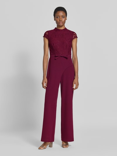 Frauenmodel trägt Regular Fit Jumpsuit mit Zierschleife von Adrianna Papell in Dunkelrot mit floralem Spitzenbesatz, Material-Mix, Ganzkörperansicht von vorne.