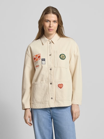 Frauenmodel trägt Regular Fit Hemdjacke mit Motiv-Patches von Jake*s Casual aus reiner Baumwolle, helle Farbe, aufgesetzte Taschen, Umlegekragen, durchgehende Knopfleiste, Ganzkörperansicht von vorne.