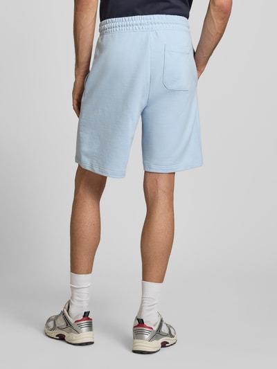 Männermodel trägt Regular Fit Sweatshorts aus reiner Baumwolle Modell 'NASENSIO' von Hugo Blue in Hellblau, unifarben, Ganzkörperansicht Rückansicht.