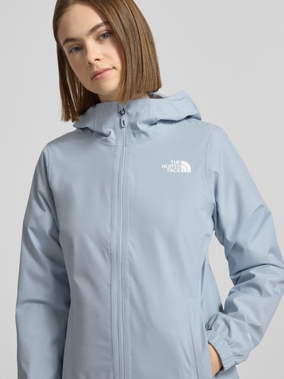 Frauenmodel trägt Funktionsjacke mit DryVent™-Technologie von The North Face in Hellblau, mit Kapuze, Reißverschluss, atmungsaktiv, Nahaufnahme Oberkörper.