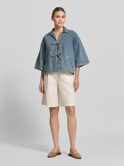 Frauenmodel trägt Jeansjacke mit Kimonoärmel Modell 'ZOE' von Mustang, Reine Baumwolle, Regular-Fit, Umlegekragen, Schnürverschluss, Seitliche Eingrifftaschen, hellblaue Waschung, lockere Form, strukturierte Denim-Textur, Rückenlänge 56 cm, Schulterbreite 44 cm, Brustweite 54 cm, Ärmellänge 43 cm, Ganzkörperansicht von vorne.