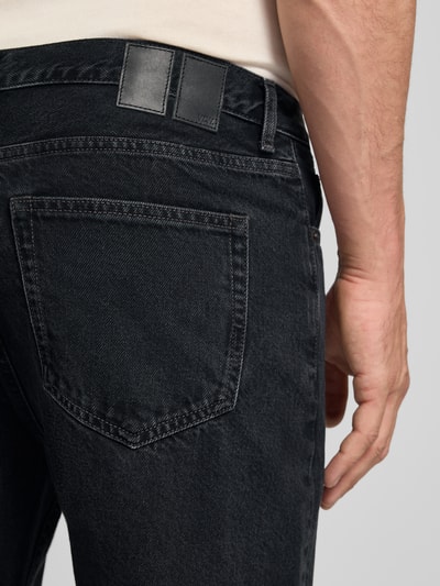 Mężczyznamodel nosi Jeans mit Eingrifftaschen Modell 'Type 2' od Wood Wood, czarny denim, szerokość w rozmiarze 32/32: 43 cm, długość nogawki: 76 cm, krój relaxed fit, detal tylnej kieszeni, zbliżenie tylnej części.
