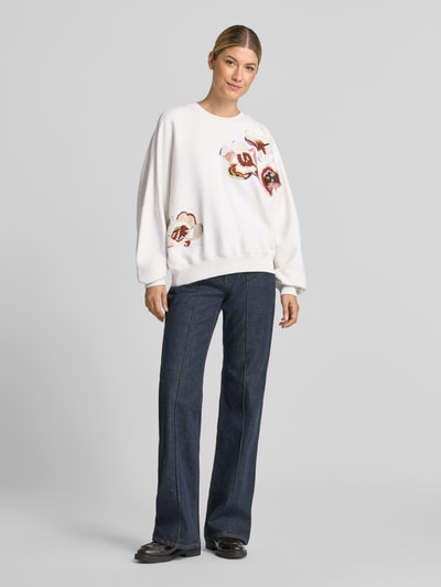 Vrouwenmodel draagt oversized sweatshirt van puur katoen Model 'ASTERA' van DRYKORN met ribboorden, rechte jeans, voorkant hele lichaam