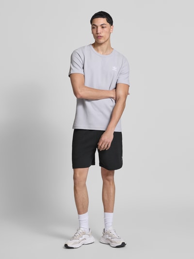 Männermodel trägt Relaxed Fit Sweatshorts mit Baumwoll-Anteil von adidas Originals, unifarben, Waffelstruktur, Ganzkörperansicht von vorne.