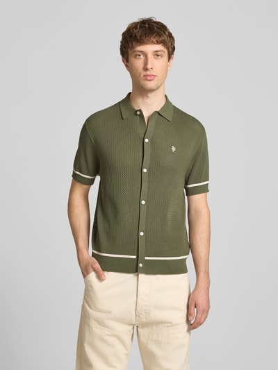 Männermodel trägt Slim Fit Strick-Poloshirt mit Label-Stitching von REVIEW, olivgrün mit Kontraststreifen, Nahaufnahme Oberkörper.