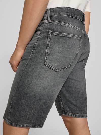 Mężczyznamodel nosi Regular Fit Jeansshorts aus reiner Baumwolle von Tommy Jeans, stylizowana na denim, naszywka z logo, 5 kieszeni, bawełna, zapięcie na guzik i zamek błyskawiczny, szlufki na pasek, wyhaftowane logo; zdjęcie z tyłu, ujęcie na całe spodnie.
