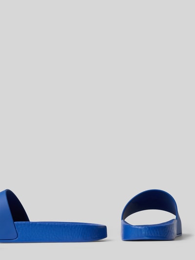 Produktfoto, Badeschuhe mit Logo-Applikation von Polo Ralph Lauren in Optik: Unifarben, Schuhspitze: Abgerundet, Absatzform: Flach, Verschluss: Schlupf/offen, Sohle: Leicht profiliert, Farbe intensiv Blau, glatte und leicht strukturierte Oberfläche