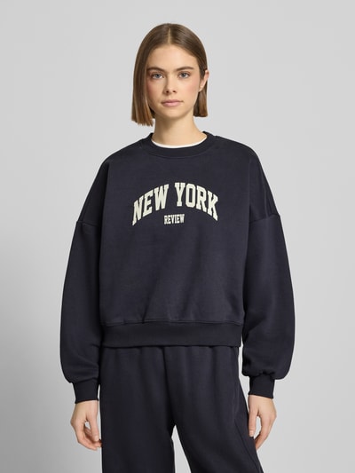 Vrouwenmodel draagt sweatshirt met labelprint en ronde hals van Review, katoenmix, relaxed fit, donkerblauw, voorkant, bovenlichaam.