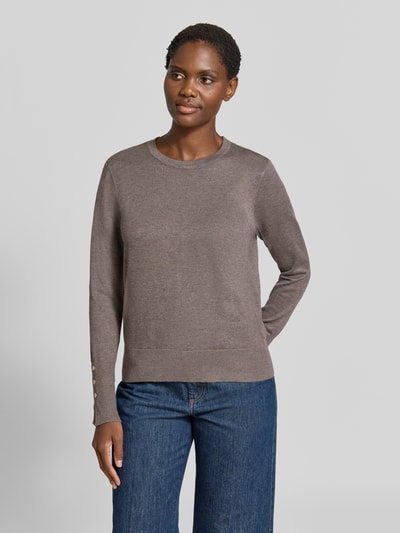 Vrouwenmodel draagt gebreide pullover van viscosemix Model 'KATIE' van FREE/QUENT, recht model, elastische boordjes, knopen aan mouwboord, ruglengte maat S 58 cm, mouwlengte maat S 66 cm, neutrale kleur, zachte textuur, voorkant gehele bovenlijf zichtbaar.