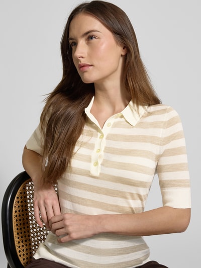 Frauenmodel trägt Regular Fit Poloshirt aus reiner Schurwolle Modell 'FIDENKA' von BOSS in Beige mit gestreiftem Allover-Muster, Feinstrick, Nahaufnahme Oberkörper.