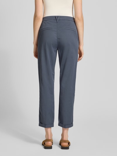 Frauenmodel trägt Straight Fit Chino in verkürzter Passform von MAC in Blau, elastischer Baumwoll-Mix, Eingriff- und Gesäßtaschen, Ganzkörperansicht Rückansicht.