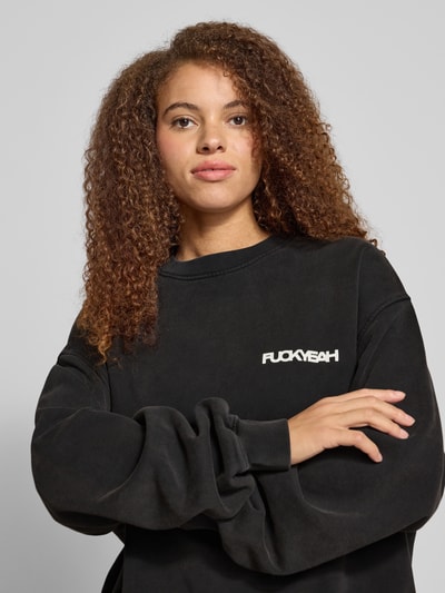 Frauenmodel trägt Oversized Sweatshirt mit Statement-Print von Karo Kauer in Schwarz, reine Baumwolle, Rundhalsausschnitt, Nahaufnahme Oberkörper.
