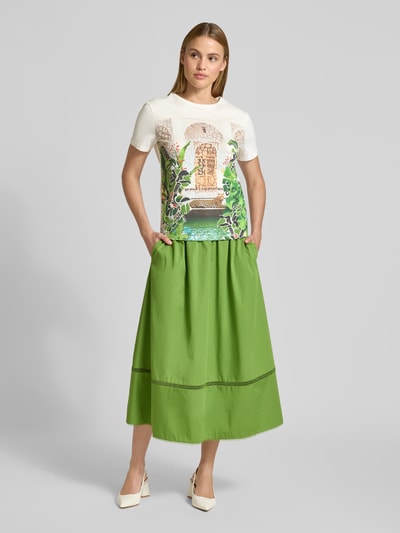 Kobiece modelka nosi Regular Fit T-Shirt mit Allover-Motiv-Print von Marc Cain z bawełny, okrągły dekolt, długość tyłu 56 cm, Ganzkörperansicht von vorne.
