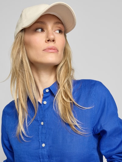Vrouwenmodel draagt Regular Fit linnen blouse met labelstitching van Gant in helderblauw met knoopsluiting, overhemdkraag, zuiver linnen, dames, ruglengte maat 36: 66 cm, mouwlengte maat 36: 60 cm, detailopname bovenlichaam.