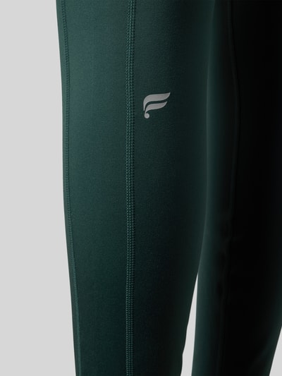Männermodel trägt Slim Fit Leggings mit Logo-Print von Fabletics, elastyczna mieszanka materiałów, krój slim fit, kieszenie na nogawkach, szeroki pas, detal nogawki, nahaufnahme nogawki