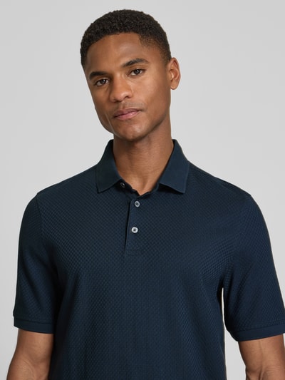 Männermodel trägt Slim Fit Poloshirt mit Strukturmuster von bugatti in Dunkelblau, reine Baumwolle, Knopfleiste, Nahaufnahme Oberkörper