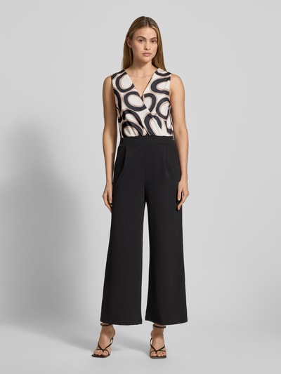 Frauenmodel trägt Jumpsuit mit Eingrifftaschen Modell 'Bi44lina' von ZABAIONE im Material-Mix mit Stretch-Anteil, weites Bein, V-Ausschnitt, creme-schwarze Farben, fließende Textur, Ganzkörperansicht von vorne. Rückenlänge 40 cm, Brustweite 35 cm, Gesamtlänge 140 cm, Innenbeinlänge 67 cm bei Größe S.