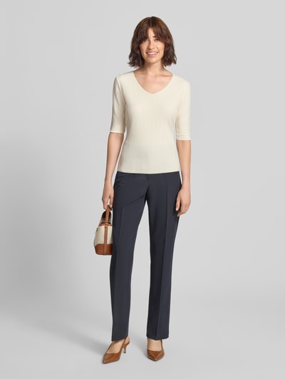 Frauenmodel trägt Regular Fit Bluse mit Strukturmuster von Emporio Armani in Beige, V-Ausschnitt, Halbarm, elastischer Material-Mix, Ganzkörperansicht von vorne.