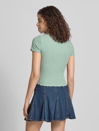 Frauenmodel trägt Slim Fit T-Shirt mit Viskose-Anteil Modell 'EMMA' von Only in Unifarben-Optik, Streifen-Struktur, Kurzarm, Rundhals, Rumpfabschluss und Ärmelabschluss mit Frill, Jacquard-Stretch Material-Mix, mintgrün, Ganzkörperansicht Rückansicht.