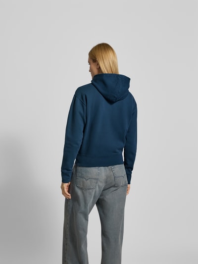 Frauenmodel trägt Regular Fit Hoodie mit Logo-Stitching von Anine Bing in Dunkelblau aus Reine Baumwolle mit Känguru-Tasche, elastische Abschlüsse, Rückenlänge bei Größe S 58 cm, Ganzkörperansicht Rückansicht.