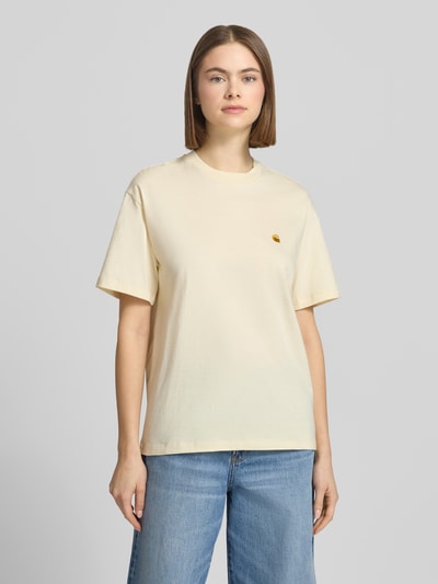 Frauenmodel trägt T-Shirt mit Label-Stitching von Carhartt Work In Progress in Creme, reine Bio-Baumwolle, Relaxed Fit, Ganzkörperansicht von vorne.