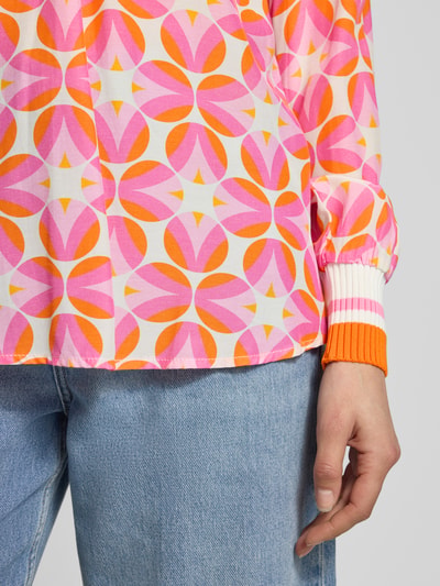 Kobieta nosi Regular Fit Bluse aus reiner Viskose von Emily Van den Bergh z geometrycznym różowo-pomarańczowym nadrukiem, elastycznym mankietem, detale tkaniny, krój regular fit, widok z przodu, zbliżenie na dolną część bluzki