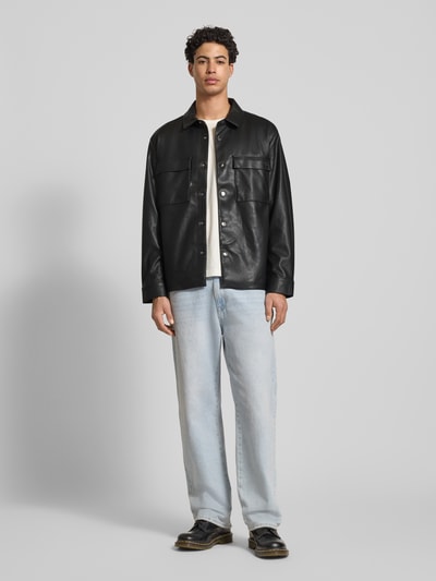 Mannelijk model draagt Regular Fit Hemdjacke in leerlook van Calvin Klein Jeans, zwarte kleur, platte kraag, borstzakken, knoopsluiting, sportmanchetten, ruglengte 73 cm, schouderbreedte 50 cm, mouwlengte 65 cm, geheel van voren te zien