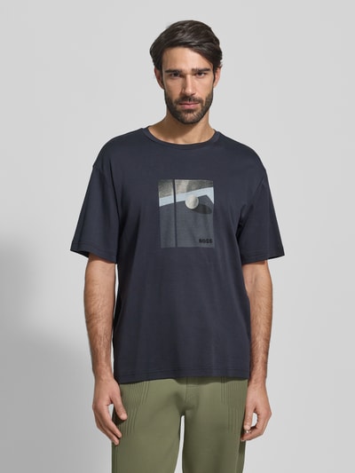 Männermodel trägt Relaxed Fit T-Shirt aus reiner Baumwolle Modell 'JOIN' von BOSS Green in Unifarbe mit Motiv-Print, Nahaufnahme Oberkörper.