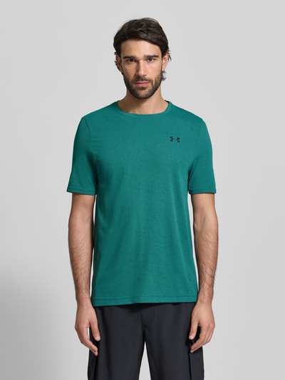 Männermodel trägt Slim Fit T-Shirt mit Logo-Print Modell 'Vanish' von Under Armour in Grün, Rundhalsausschnitt, Lochmuster, Ganzkörperansicht von vorne