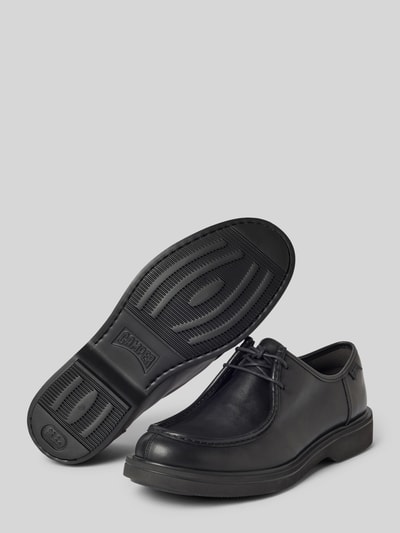 Produktfoto, schwarze Schnürschuhe mit Label-Detail Modell 'Norman' von Camper aus Leder, abgerundete Spitze, Gummisohle mit Profil, Größe 44: Absatzhöhe 3 cm, Schafthöhe 6 cm, Schaftweite 12 cm, glatte Textur, neutrale Hintergrundfarbe.