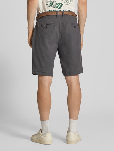 Männermodel trägt Bermudas mit Gürtel und Eingrifftaschen Modell 'NEBRASKA' von Redefined Rebel aus Baumwoll-Mix mit Stretch-Anteil, Ganzkörperansicht Rückansicht.
