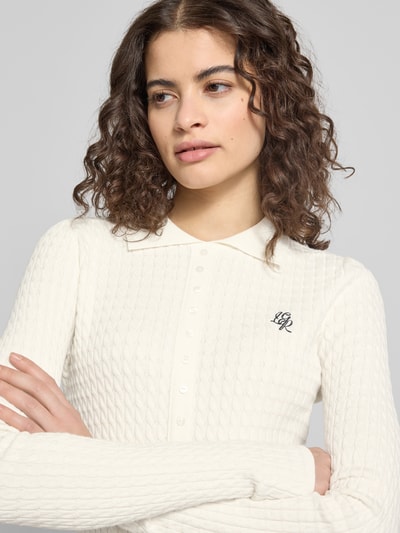 Vrouwenmodel draagt Cardigan met Logo-Stitching model 'Manolja' van LeGer by Lena Gercke in wit met kentkraag en knoopsluiting, shetlandwolmix met viscose, aansluitende fit, logo op borst, detailopname bovenlichaam.