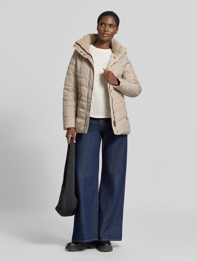 Kobiece modelka nosi 'Jacke in Stepp-Optik mit Kapuze' od FUCHS SCHMITT, beżowa, z efektem pikowania, taliowany krój, kaptur, ocieplany stójka, wpuszczane kieszenie z zamkiem błyskawicznym, długość tyłu w rozmiarze 36: 74 cm, szerokość ramion w rozmiarze 36: 40 cm, szerokość klatki piersiowej w rozmiarze 36: 48 cm, długość rękawów w rozmiarze 36: 64 cm, cała sylwetka z przodu.