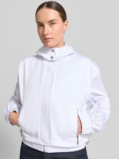 Frauenmodel trägt Jacke mit Stehkragen und verdecktem Reißverschluss von monari in Weiß, strukturierte Oberfläche, Reißverschlusstaschen, Regular-Fit, Rückenlänge 49 cm, Schulterbreite 55 cm, Brustweite 57 cm, Ärmellänge 58 cm, Ganzkörperansicht von vorne.