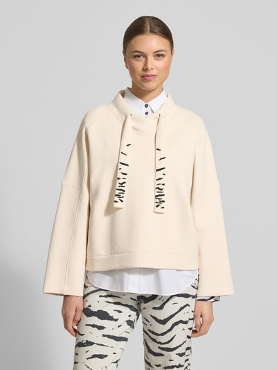 Kobiece modelka nosi Oversized Sweatshirt mit Tunnelzug von Marc Cain, mieszanka bawełny z dodatkiem streczu, krój oversized, stójka, tunel, kremowy kolor, przód z przodu, zbliżenie na górną część ciała.
