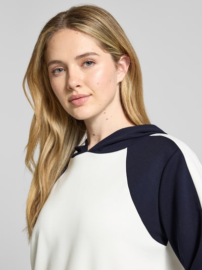 Vrouwenmodel draagt Relaxed Fit Sweatshirt met Viskose-Anteil van monari in zwart-wit met capuchon, elastische mix, close-up bovenlichaam.
