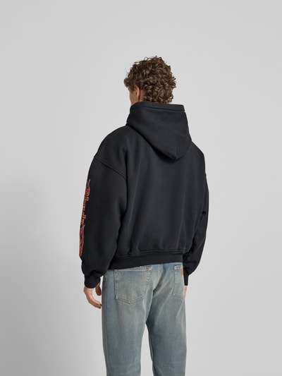 Männermodel trägt Hoodie mit Kapuze von RHUDE in Schwarz, Reine Baumwolle, Lockerer-Schnitt, Label-Print, Känguru-Tasche, Rückenlänge 61 cm, Ganzkörperansicht Rückansicht.