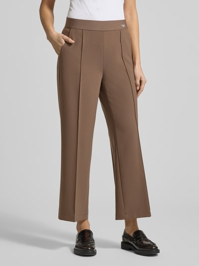 Kobiece modelka nosi spodnie materiałowe z ozdobnym szwem Straight Fit model 'Cameron' od Cambio, skrócony krój, elastyczny pas, kieszenie z tyłu, nadruk z logo, kolor brązowy, szerokość w rozmiarze 36: 39 cm, długość wewnętrzna nogawki w rozmiarze 36: 67 cm, widok z przodu, detal nogawki.
