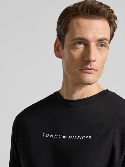 Männermodel trägt Regular Fit T-Shirt aus reiner Baumwolle von Tommy Hilfiger in Schwarz mit Label Print, Nahaufnahme Oberkörper.