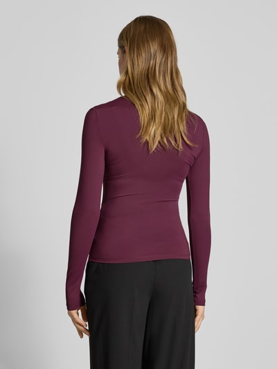 Frauenmodel trägt Slim Fit Langarmshirt mit Rundhalsausschnitt Modell 'LULA' von Pieces, unifarben, Stretch-Webstruktur, Ganzkörperansicht Rückansicht.
