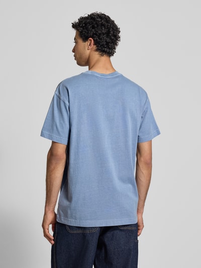 Männermodel trägt T-Shirt mit Label-Detail Modell 'Nelson' von Carhartt Work In Progress in Hellblau, lockerer Schnitt, Baumwolle, Ganzkörperansicht Rückansicht.